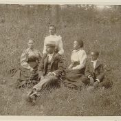 African American family posed for portrait seated on lawn.